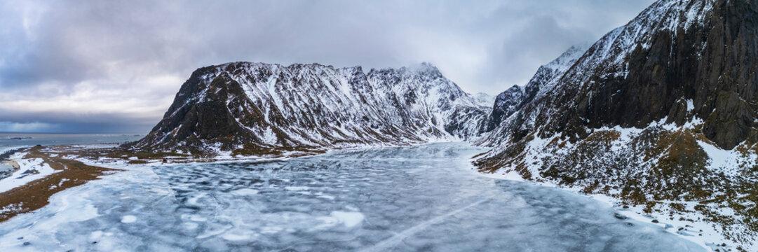 Frozen lake with snowy mountains at eggum nature reserve in Lofoten