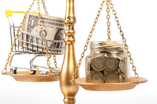 A glass jar containing 100 Kazakhstani tenge coins and a stack of US 1 dollar bills, placed on the pans of a golden balance scale.