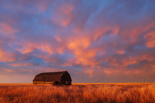 Old barn with dramatic Sunset clouds in oklahoma grassland