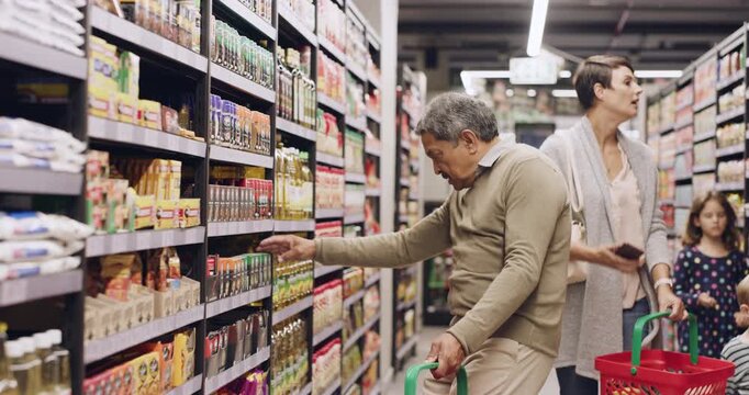 Senior, man and search in supermarket for shopping, seasoning selection or nutrition value on herbs. Independent living, pensioner and basket for retail, spices choice or read label for managing diet