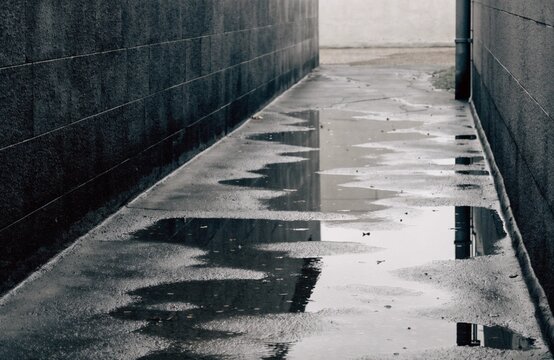 Rain soaked narrow alley between concrete walls on an overcast day