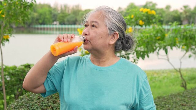 Refreshing Sip: An older individual takes a revitalizing drink from a bottle, enjoying a moment of wellness and health in the vibrant outdoor setting.