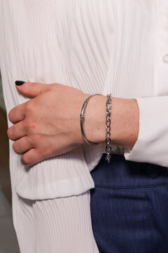 Close-up of a woman&rsquo;s wrist wearing two elegant silver-tone bracelets, styled with a white blouse in a modern fashion jewelry look.