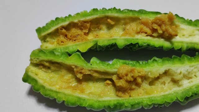 Rotting bitter melon fruit decaying over time in a cross section view, isolated on a white background, demonstrating the process