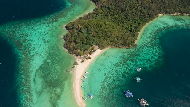 Drone footage of Bulog Dos Island, a popular island-hopping destination near Coron, Palawan, showing the island's distinctive sandbar, shallow turquoise waters, coral reefs and tropical landscape.