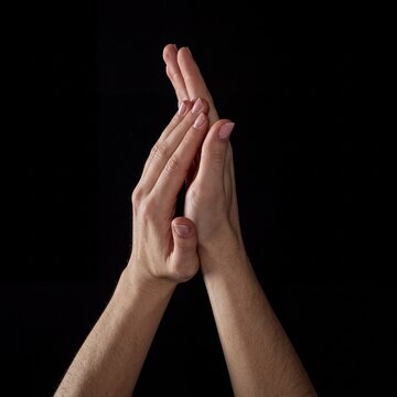 Close-up of two hands touching fingers together in a gesture symbolizing connection and unity on black background