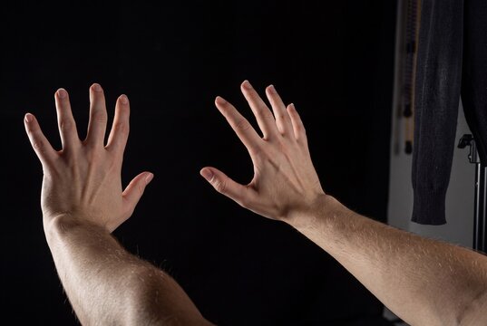 Close-up of human hands displaying expressive open palm gestures isolated on black background