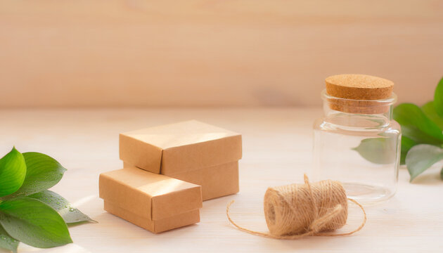 Small cardboard packaging boxes and a corked glass jar sit alongside twine and green leaves.