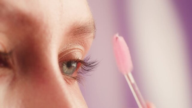 Makeup artist styling and shaping eyebrows of young teenager student model, brow correction for fashion photo shoot on pink background