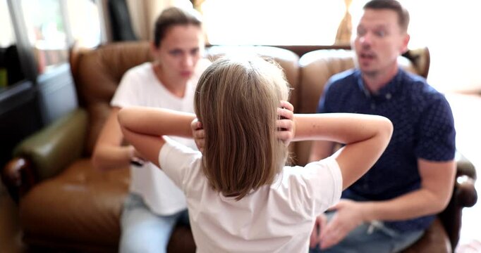 In a warm living room, a young girl holds her ears, overwhelmed by her parents' animated conversation. They appear upset, discussing matters that trouble the family dynamic.