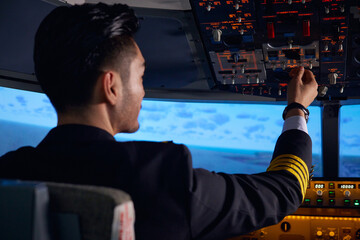 Airline pilot operating cockpit controls during flight © LeNgoc