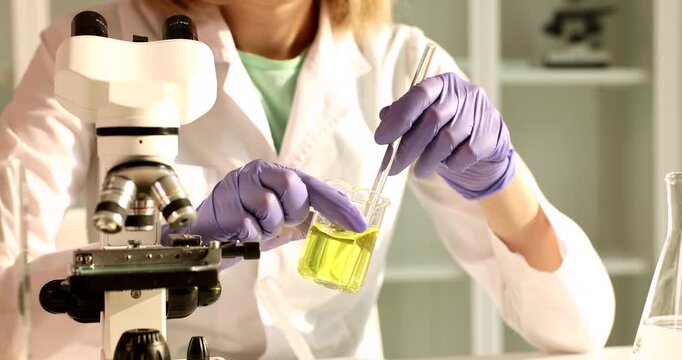 A scientist in a laboratory carefully conducts experiments with a microscope and beakers, observing the changes in the contents as they mix. The focus is on precision and detail.