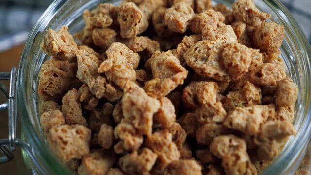 Close-up of dry soy meat stored in a glass jar, a plant based protein alternative for vegetarian meals.