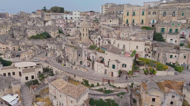Aerial flight, Panoramic drone view of Matera, South Italy, showing its historic stone houses, tiled rooftops and the imposing Matera Cathedral rising above the ancient Sassi district.