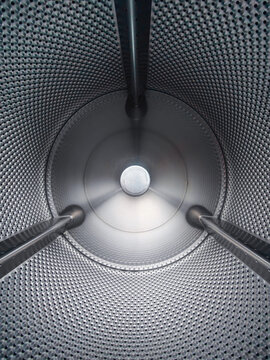 Interior of a large stainless steel commercial washing machine drum with perforated metal walls. Stainless steel perforated industrial drum