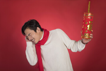 Man Covering Ears While Holding Large Red Chinese New Year Firecracker © LaDieuNgoc
