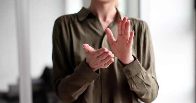 In a well-lit space, a person claps their hands softly, creating a gentle sound. The movement is smooth and rhythmic, reflecting joy and engagement in the moment.