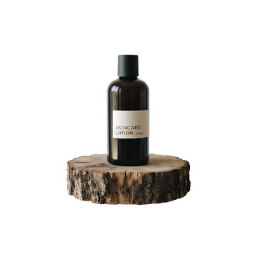 Skincare lotion bottle on a natural wooden pedestal PNG. Amber glass cosmetics container with label designed for organic beauty branding. Template for sustainable cosmetic products PNG