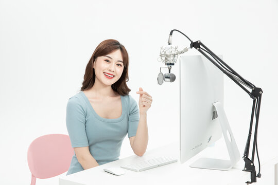 Smiling Asian Woman Making Heart Gesture During Online Live Broadcast with Microphone