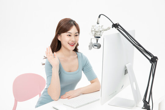 Smiling Asian Woman Waving During Online Live Broadcast at Desk