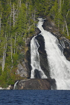 Waterfall flowing through a forested rocky landscape