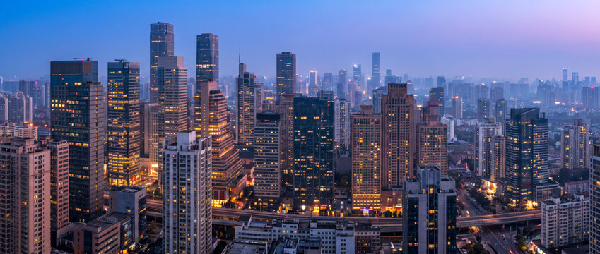 Dense downtown skyline stretches toward a hazy horizon above a busy highway interchange
