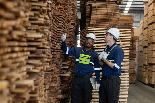 Workers discussing tasks in a wood storage area in a warehouse