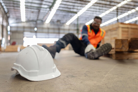 Close-up on white hard hat with blurred injured factory worker on the floor