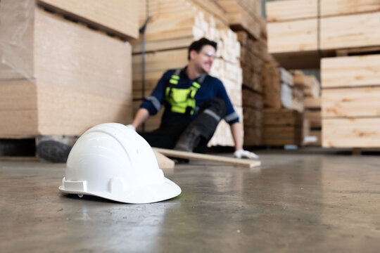 Close-up on white hard hat with blurred injured factory worker on the floor