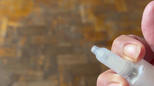 Close up of woman hand holding a plastic dispenser nozzle and spraying medical fluid. Health care routine, allergy relief treatment, rhinitis or common cold remedy concept.