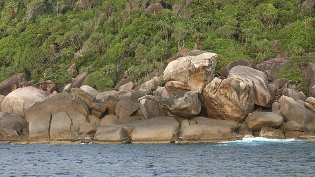 View of Similan Islands granite boulders along the coastline with lush tropical forest and clear sea in Lam Kaen, Phang Nga, Thailand.