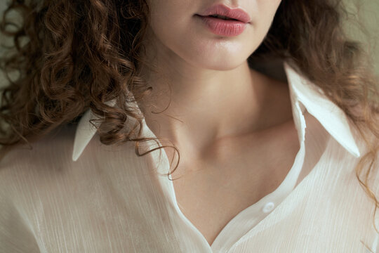 Close up Woman with curly hair in white shirt posing indoors