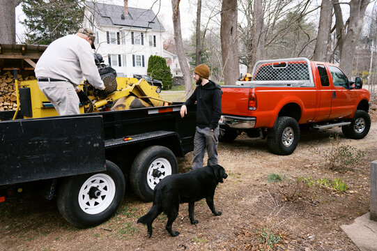 working men talking while loading machinery onto trailer
