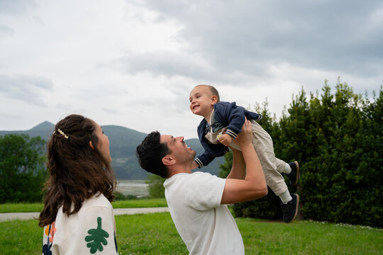 Father lifting happy baby son high in air