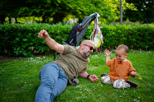 Father and baby playing together in green park grass