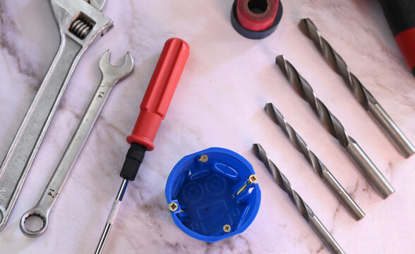 Tools and materials are arranged on a work surface for a home repair task in a workshop setting