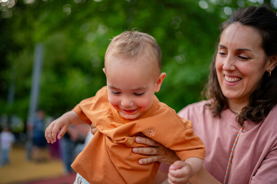 Mother holding happy baby playing in park