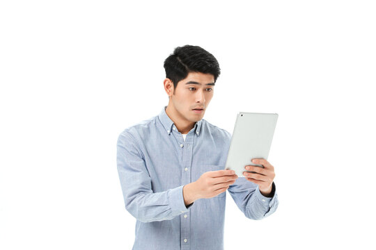 Surprised Young Asian Man in Blue Shirt Holding Tablet and Reacting with Shock