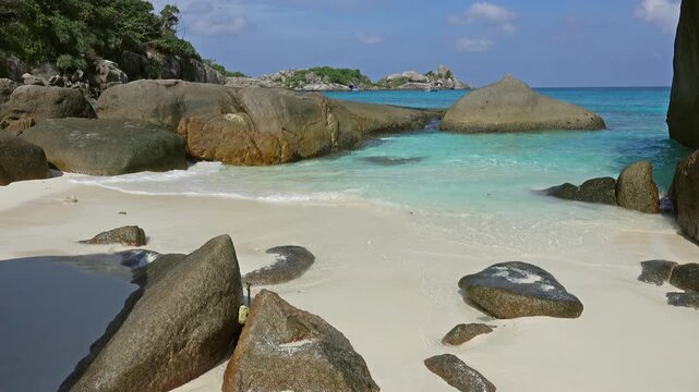 View of the turquoise waters and white sand beach framed by large granite boulders at Similan Islands in Lam Kaen, Phang Nga, Thailand.