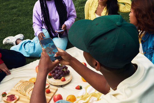 Young man taking a photo of a picnic with his friends