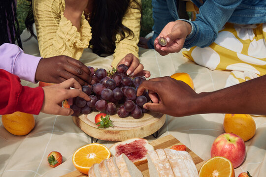 Diverse hands sharing fruit during outdoor picnic lunch