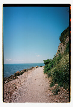 A gravel coastal path curves beneath a rocky cliff
