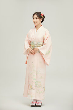 Smiling Japanese Woman Wearing a Pink Floral Kimono in a Studio Portrait