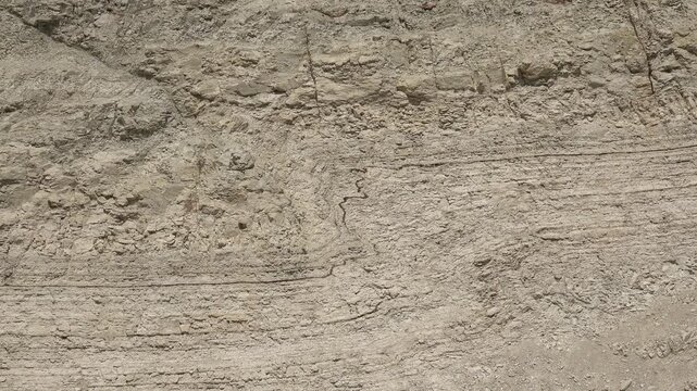Folded soil layers reveal erosion marks in cross section, exposed earth showing ground movement.