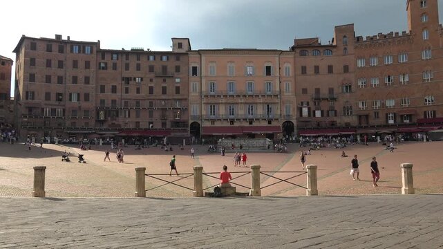 Piazza del Campo fills Siena Italy, medieval square animated by crowd movement and city life.