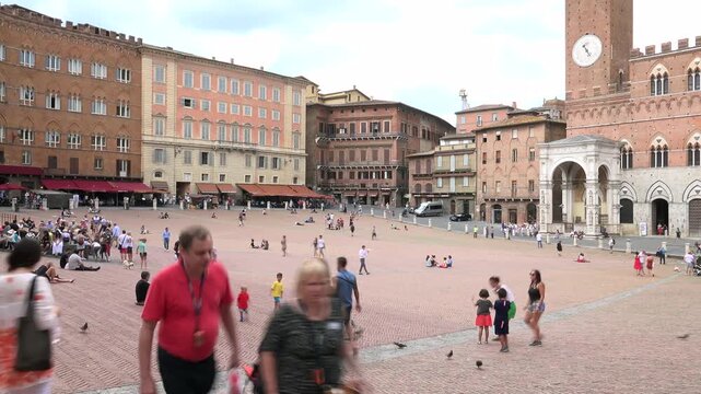 Piazza del Campo fills Siena Italy, medieval square animated by crowd movement and city life.
