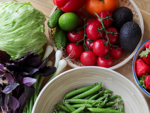 Fresh raw vegetables in bowls on wooden table