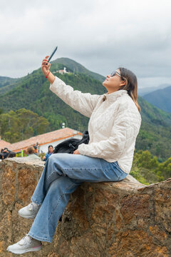Latina woman traveling, taking selfie on monserrate hill, bogota