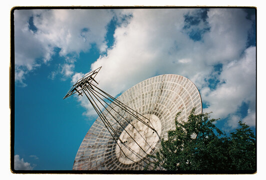 A large radio telescope dish pointed at a cloudy blue sky