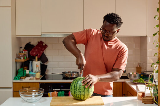 A man cuts a fresh watermelon at home